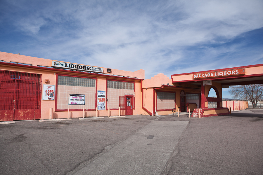 Pink roadside liquor store complex around an empty parking lot.