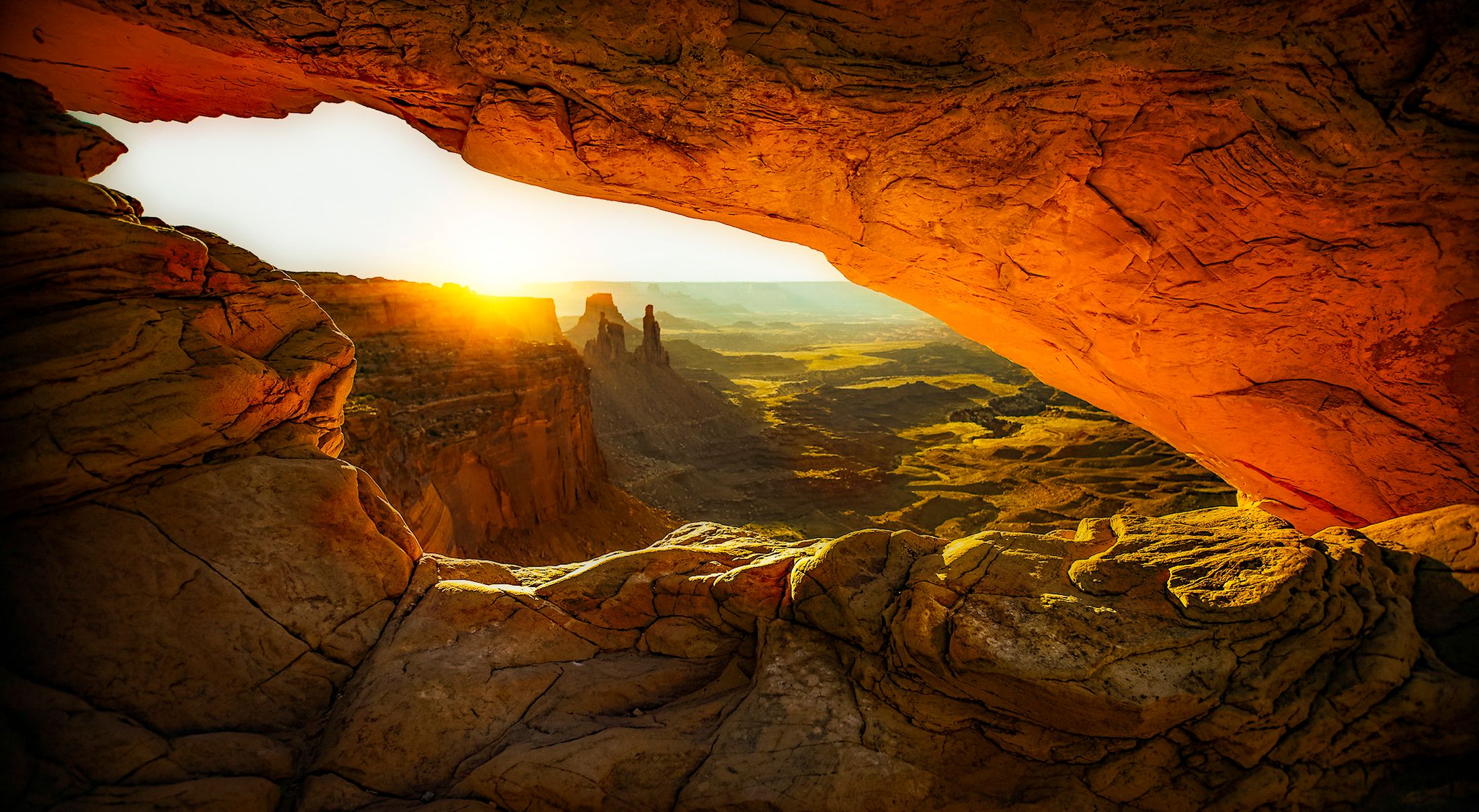 Sunrise shining through Mesa Arch onto the sandstone canyons of Canyonlands National Park, Utah.