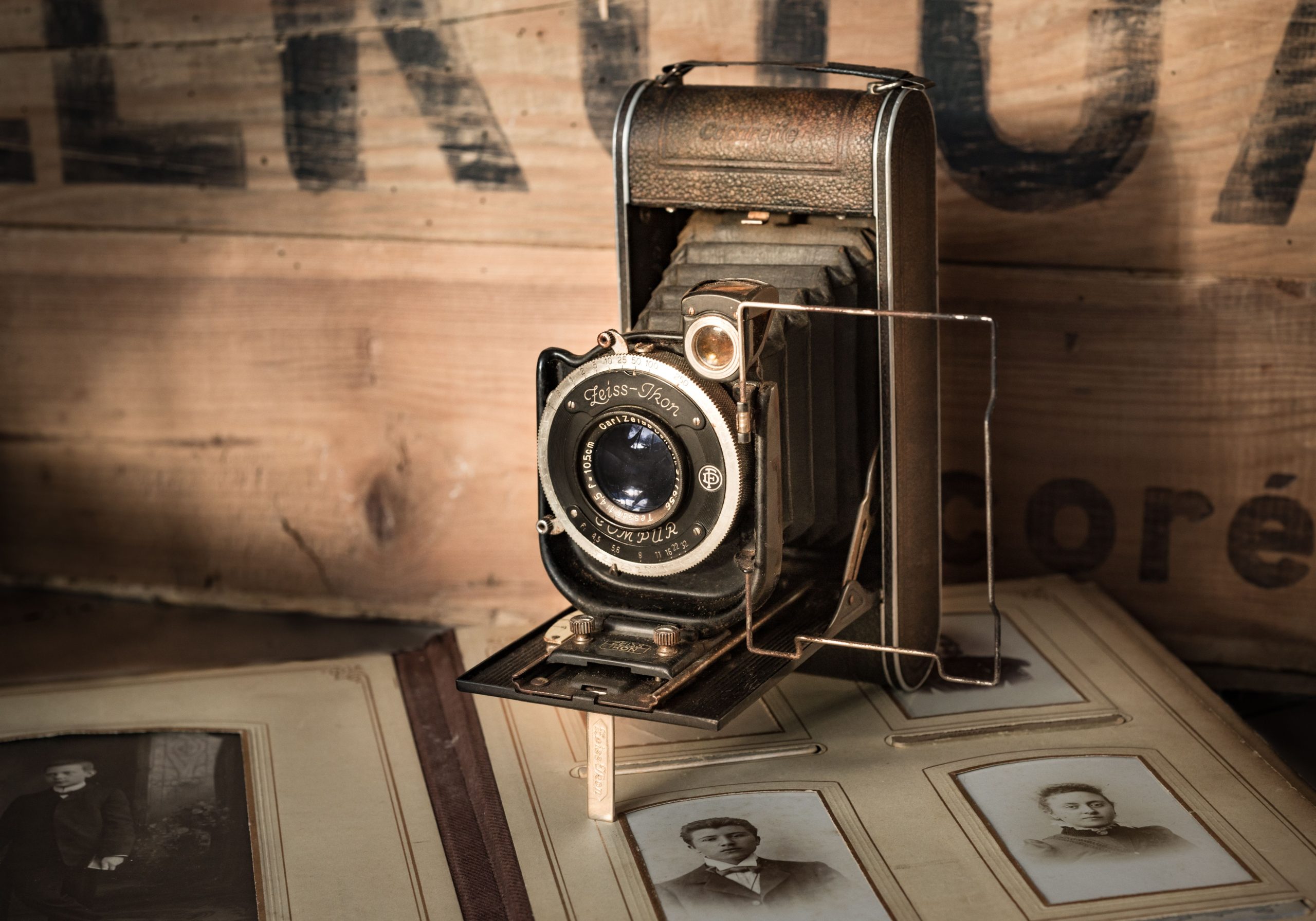 Vintage folding camera on old photographs and books