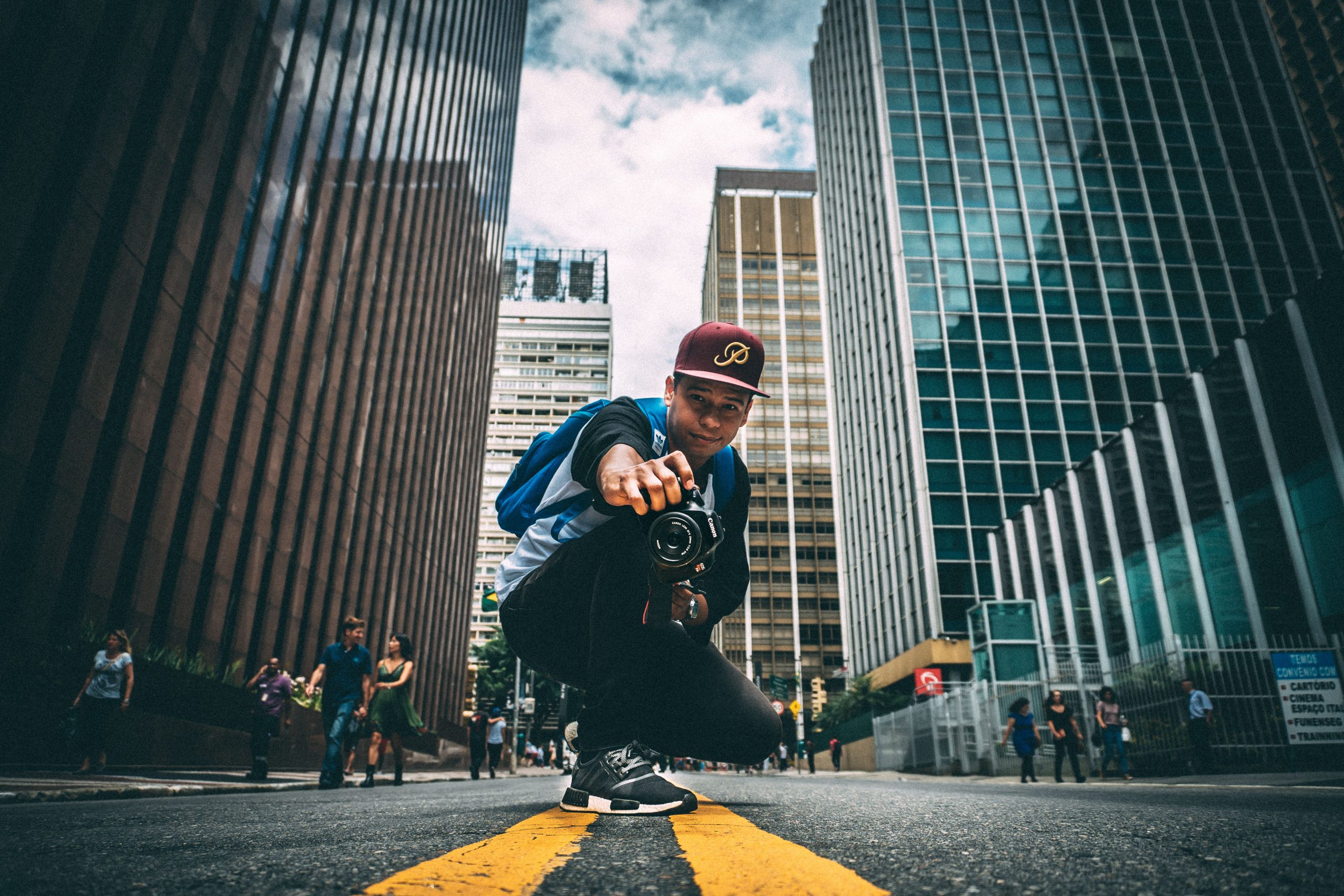 Photographer crouching beside a yellow street line between city buildings