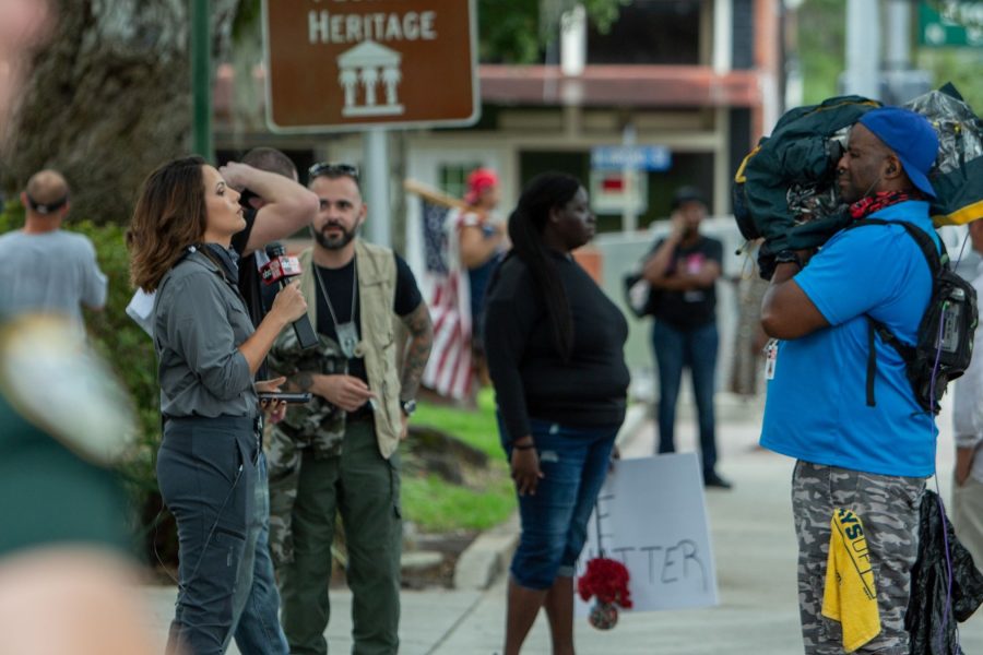A television camera operator films a reporter at a street demonstration.