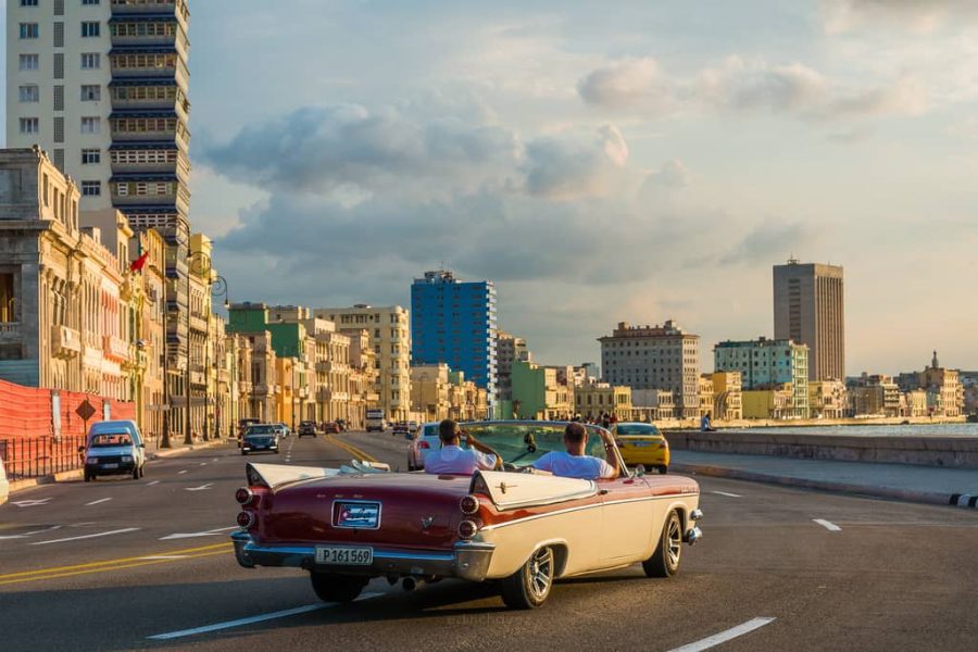 Vintage convertible driving along the Malecon seafront in Havana, Cuba, in golden light