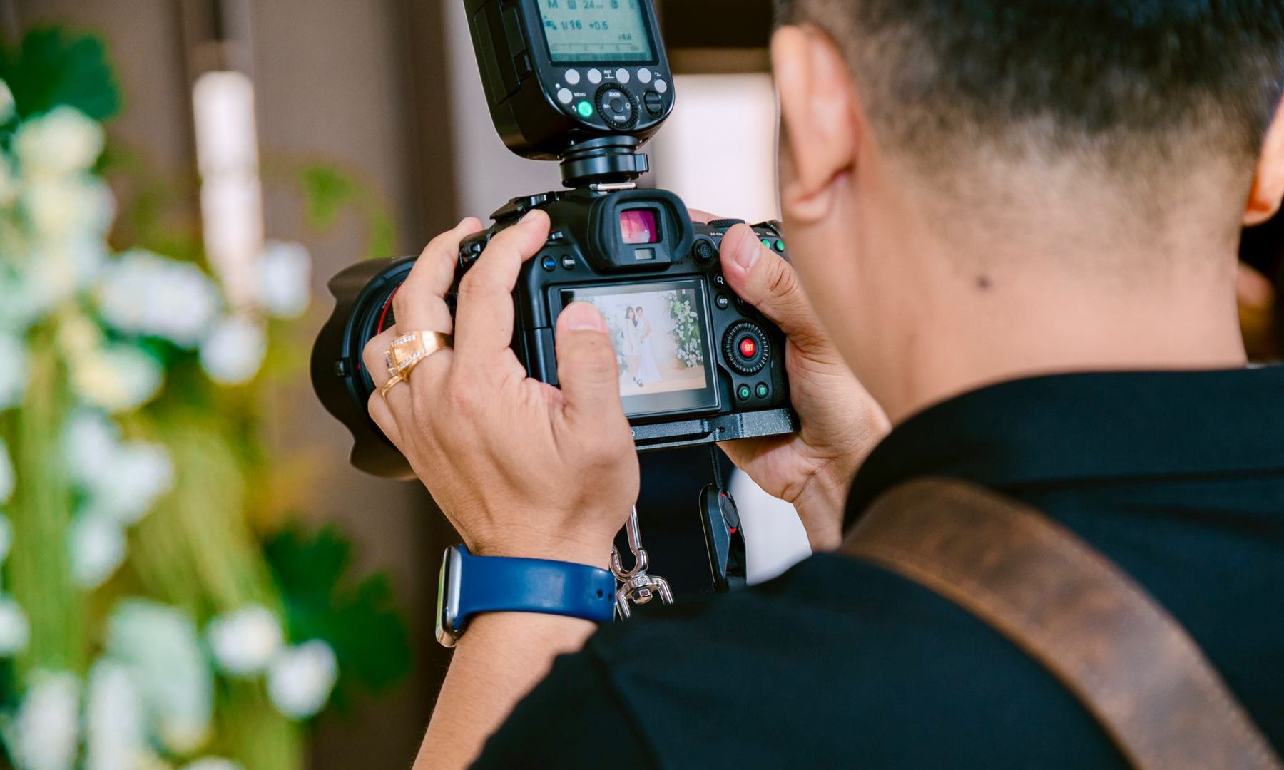 Event photographer using a camera and mounted flash at an indoor celebration