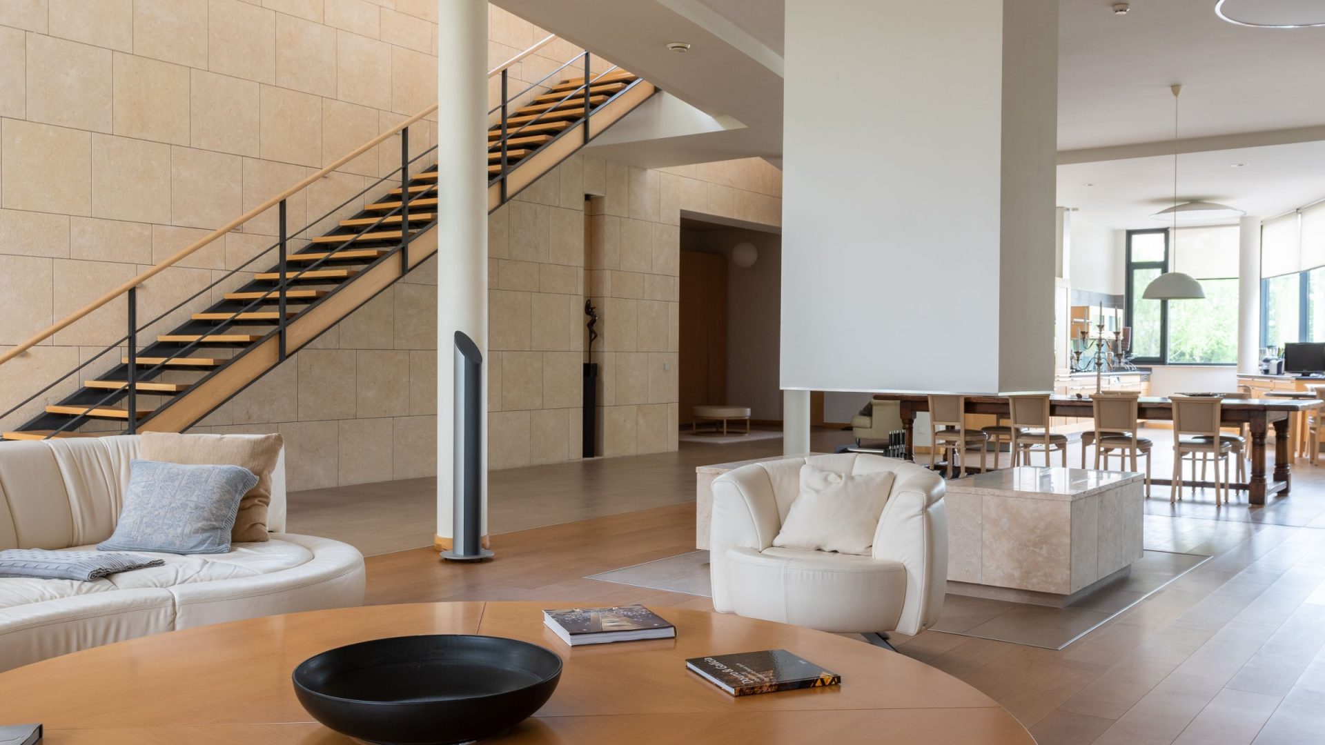 Spacious modern living room with white seating, an open staircase and dining area
