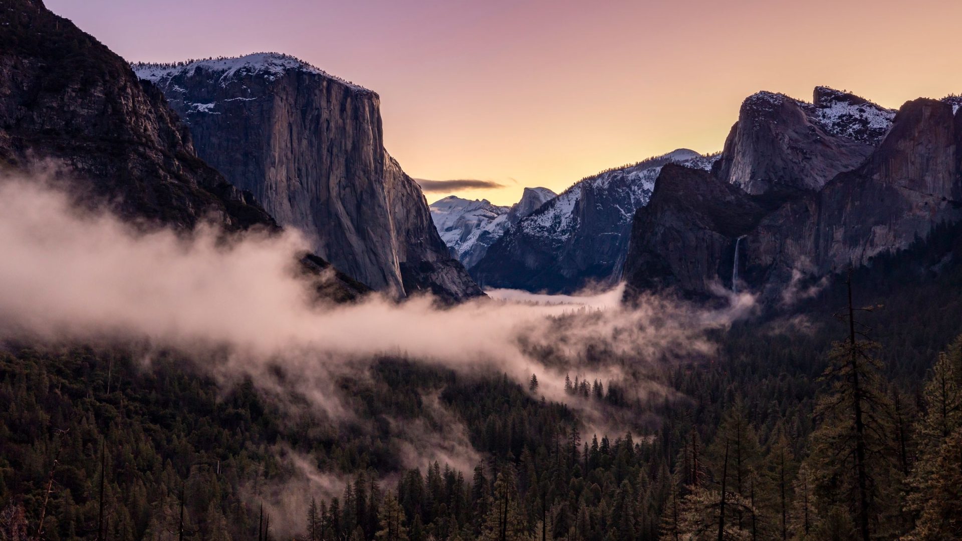 Mist drifting through Yosemite Valley between granite cliffs at sunset