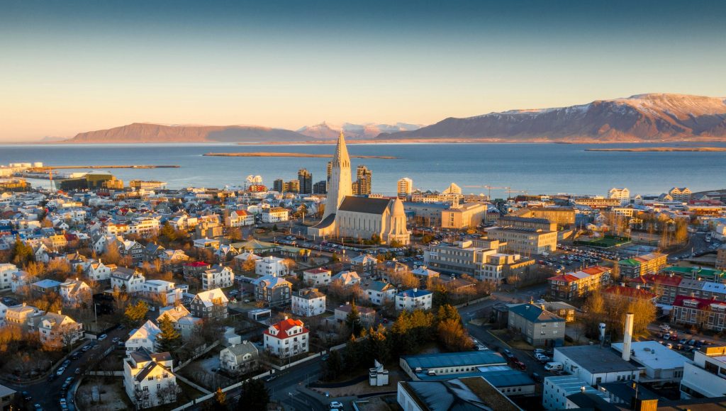 Reykjavik rooftops and Hallgrímskirkja at golden hour, with Mount Esja across the bay