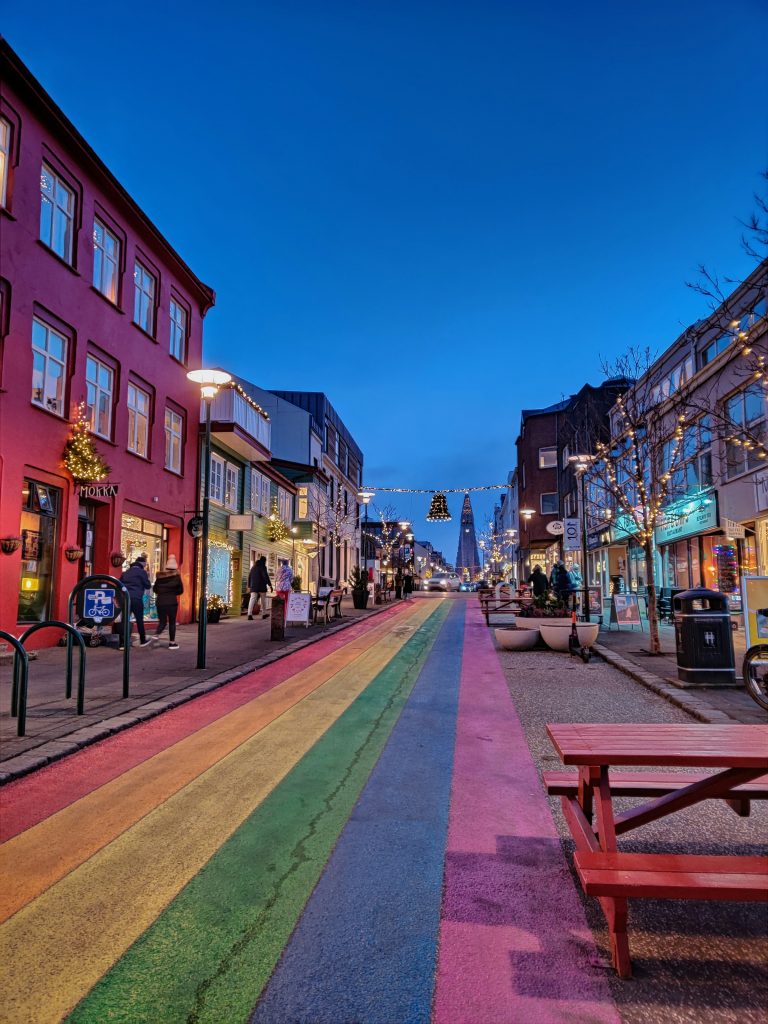 Rainbow-painted street in downtown Reykjavik at blue hour, leading toward Hallgrímskirkja