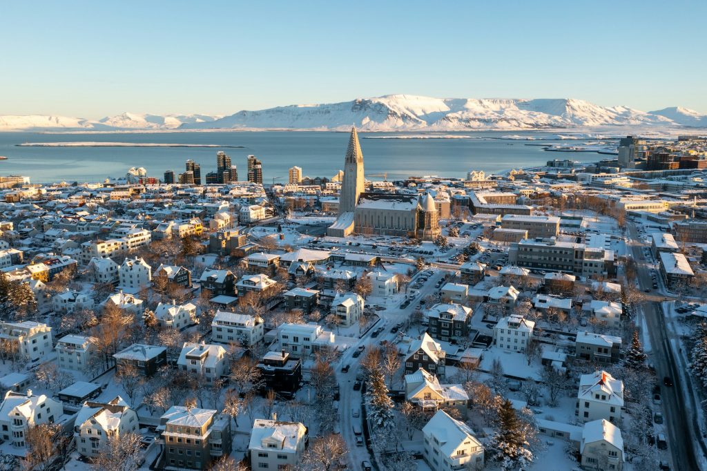Snow-covered Reykjavik rooftops from above with Mount Esja across the bay