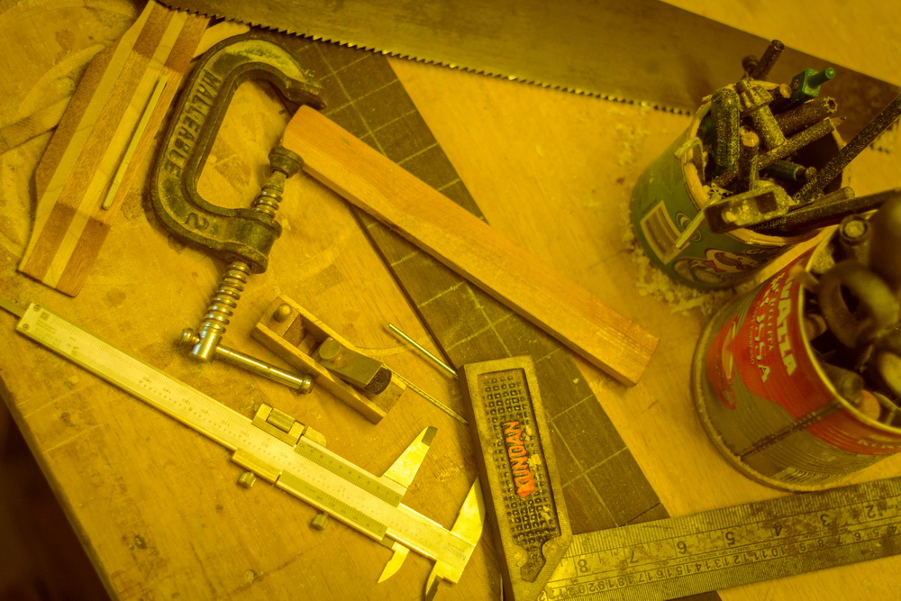 Overhead view of woodworking tools, clamps, and a saw on a workbench.
