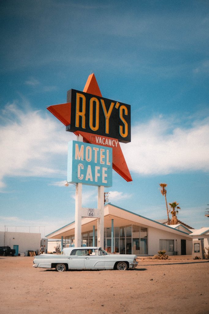 Roy's Motel and Cafe sign beside a classic car along Route 66 in the California desert.