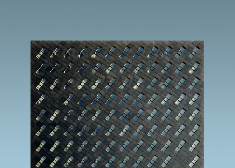 Dark grid facade against cyan sky