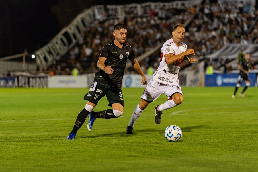 Two soccer players battling for the ball under stadium lights