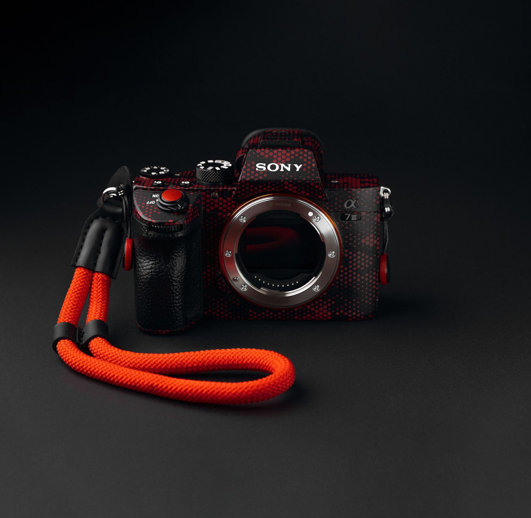 Sony Alpha 7 III full-frame mirrorless camera body with a red wrist strap against a black background.