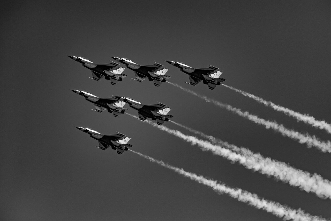 Six Thunderbird jets flying in formation with smoke trails