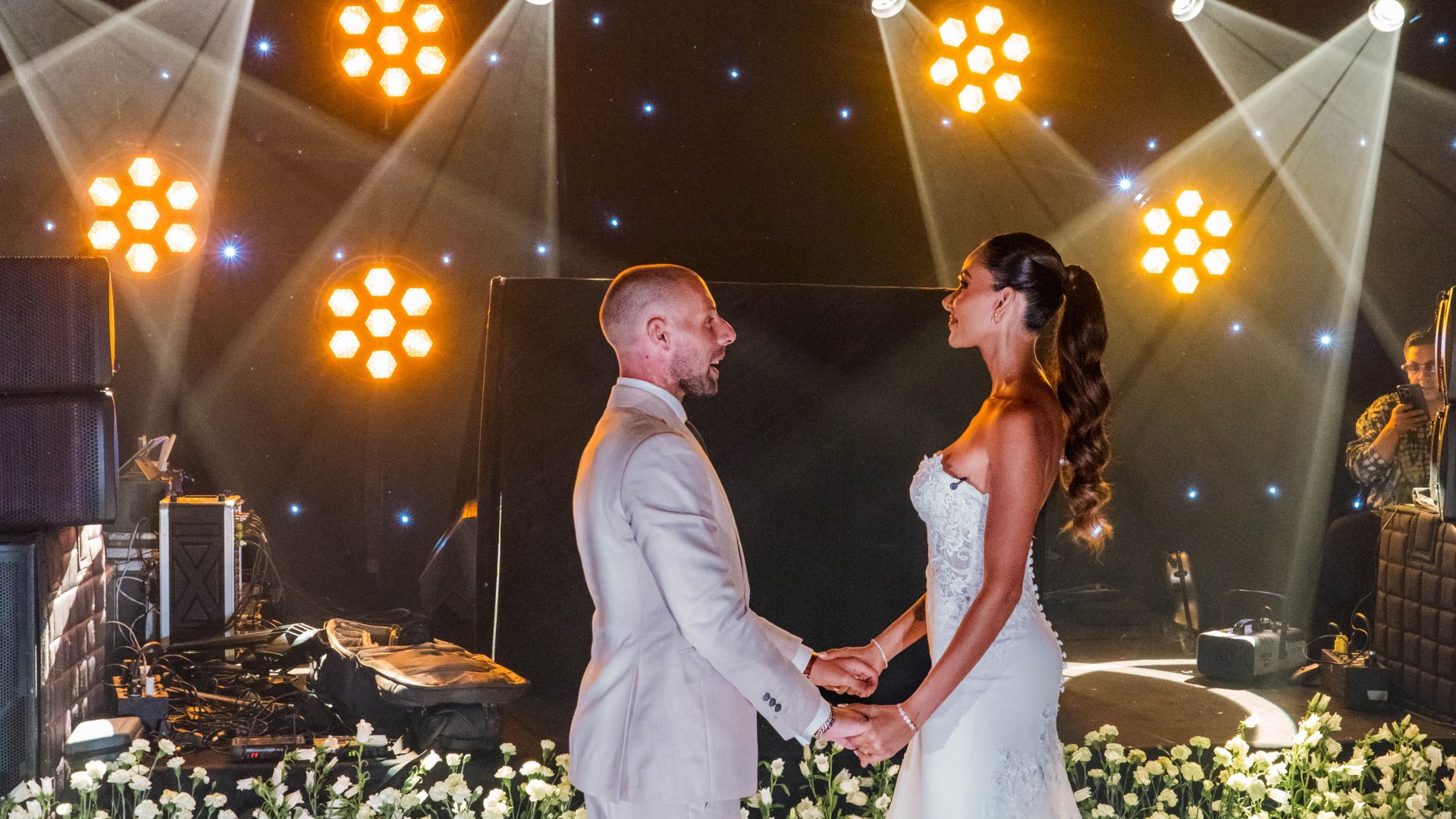 Bride and groom holding hands under stage lights at their wedding reception