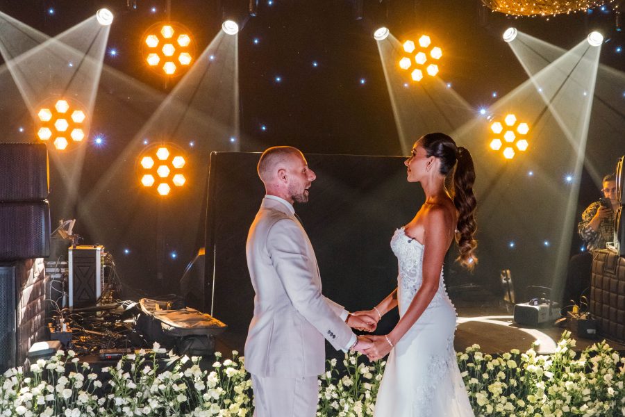 Bride and groom holding hands under stage lights at their wedding reception