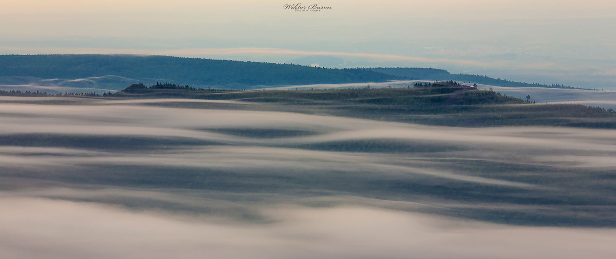 Mountain ridge emerging above a low blanket of cloud.