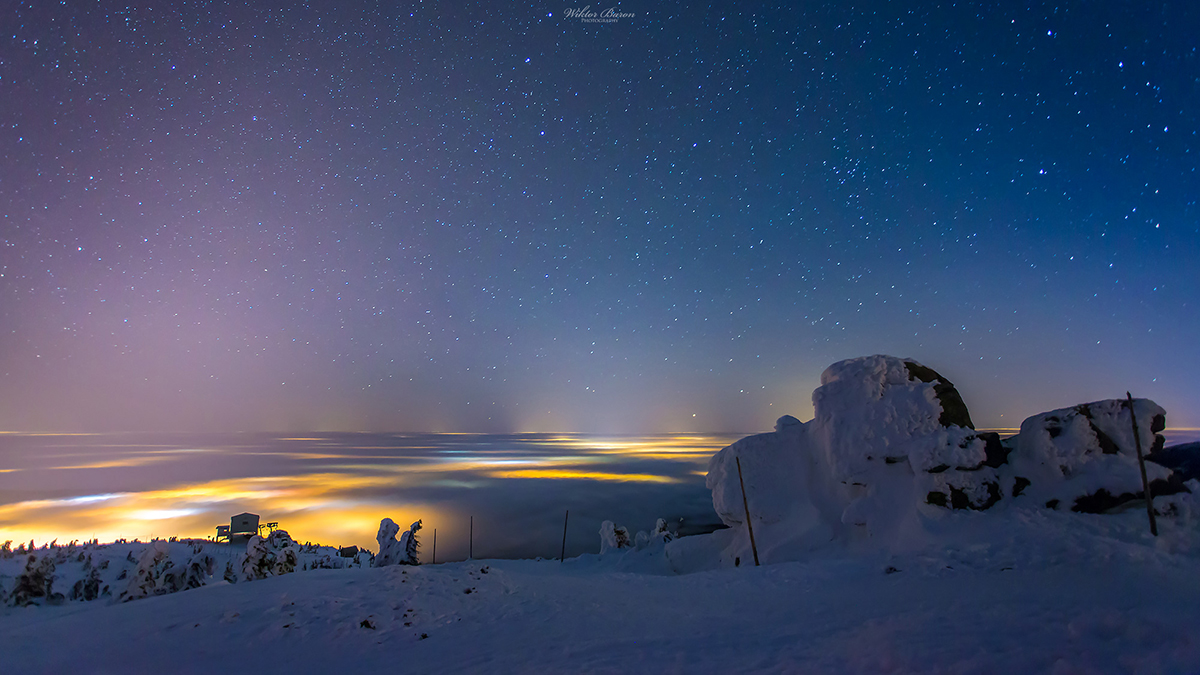 Snow-covered mountain rocks beneath a starry sky.