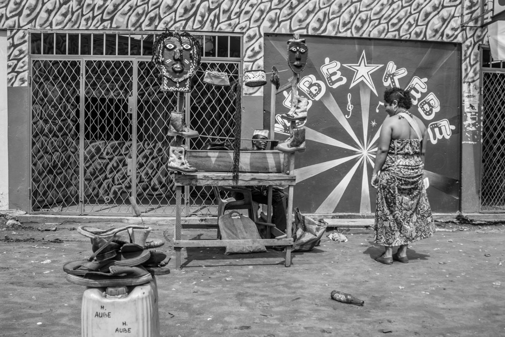 Person stands beside a painted wall and a small cart.