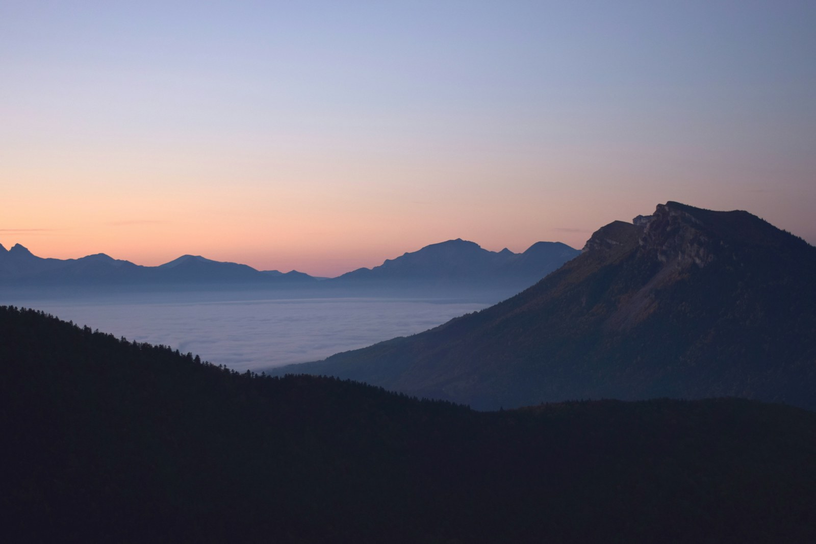 Dusk mountain ridge above a sea of cloud with pastel sky, long exposure fog photography inspiration