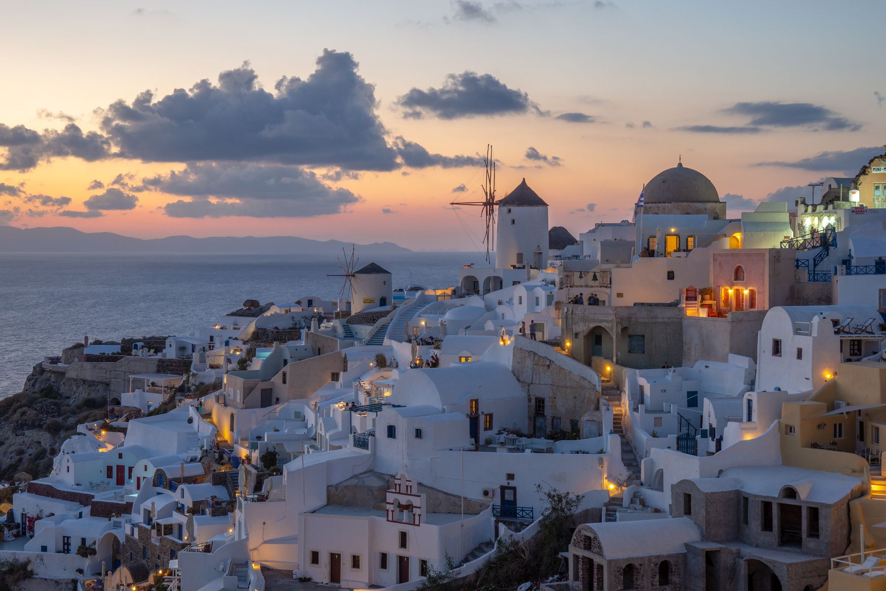 Whitewashed houses of Oia on Santorini glowing at dusk above the caldera