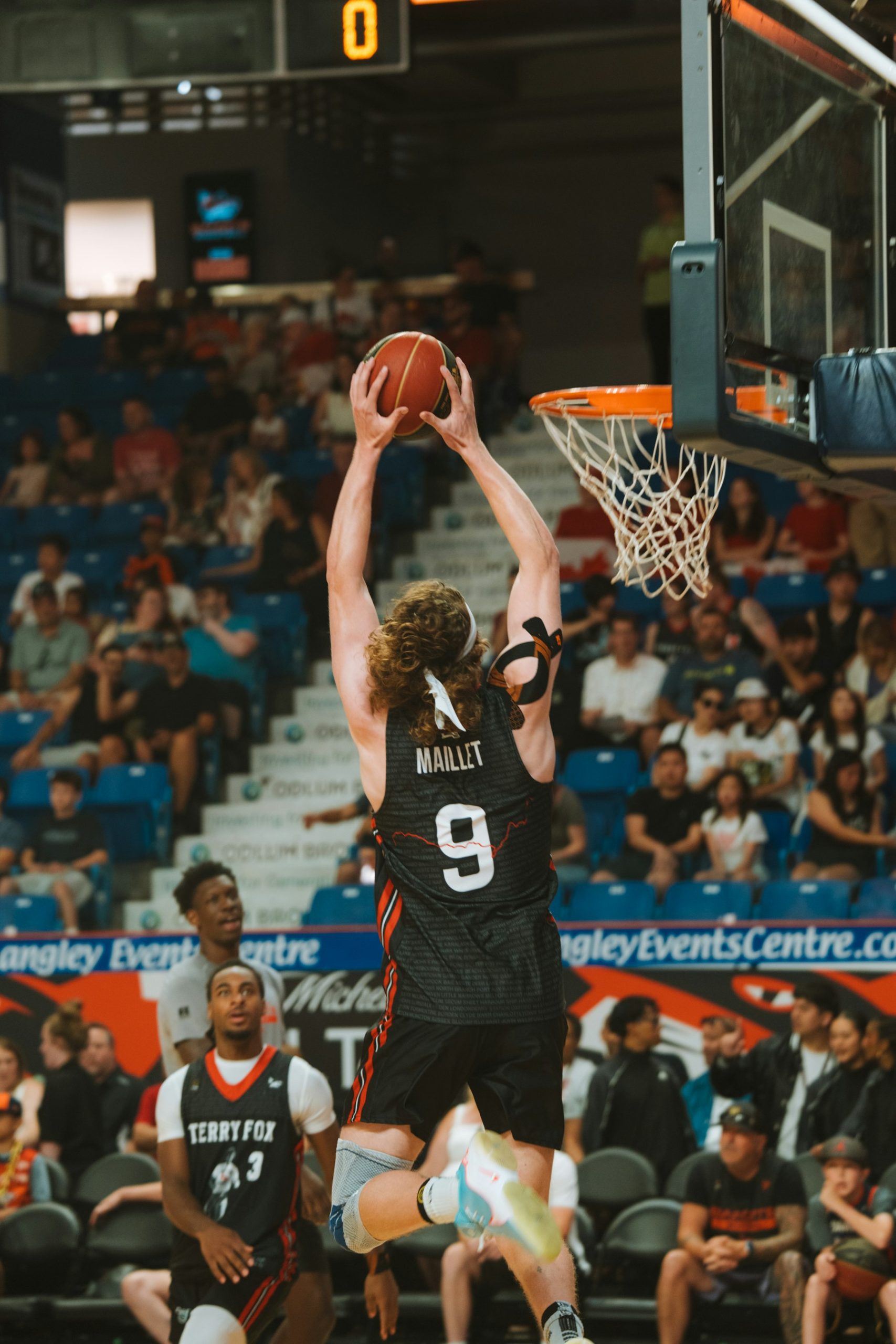 Basketball player in a black number nine jersey jumping toward the basket with the ball raised.
