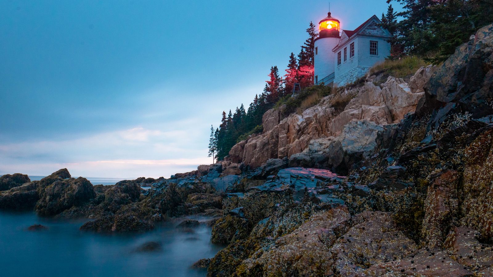 Bass Harbor Head Light glowing at blue hour above the rocky Acadia coast