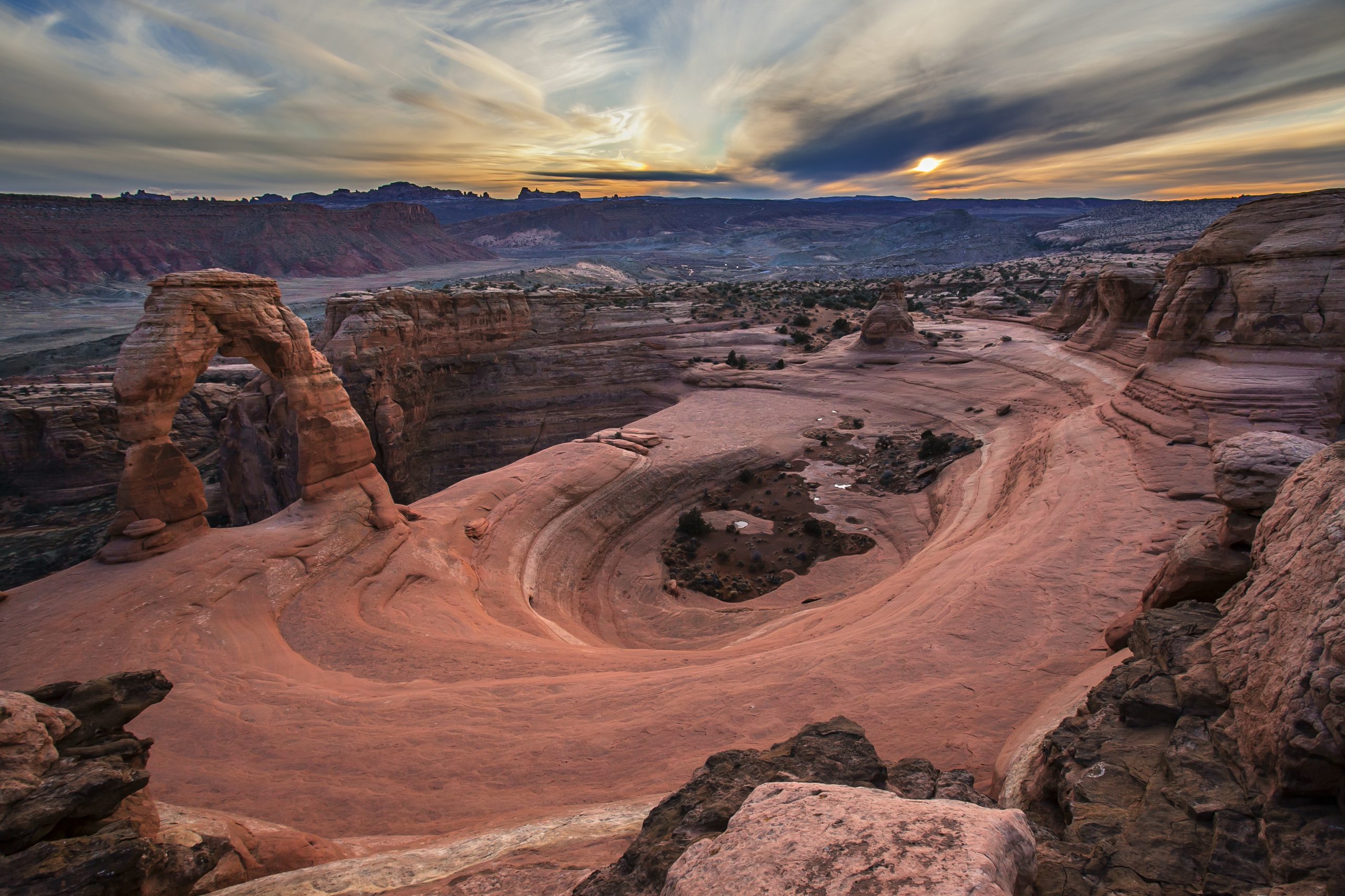 Delicate Arch at sunset above the slickrock basin in Arches National Park