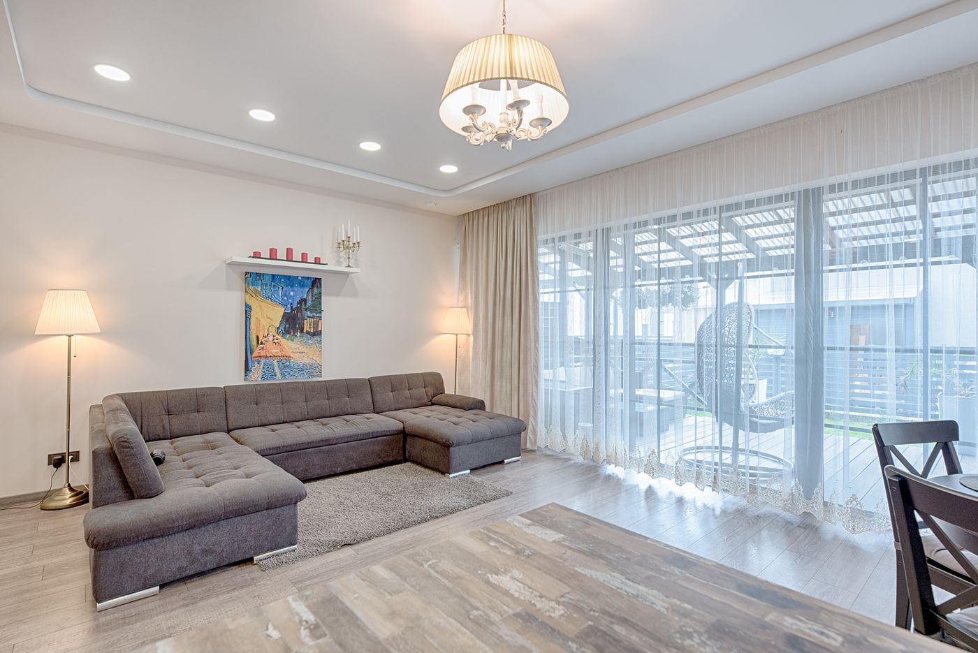 Bright living room with a gray sectional sofa, large windows and light wood floor