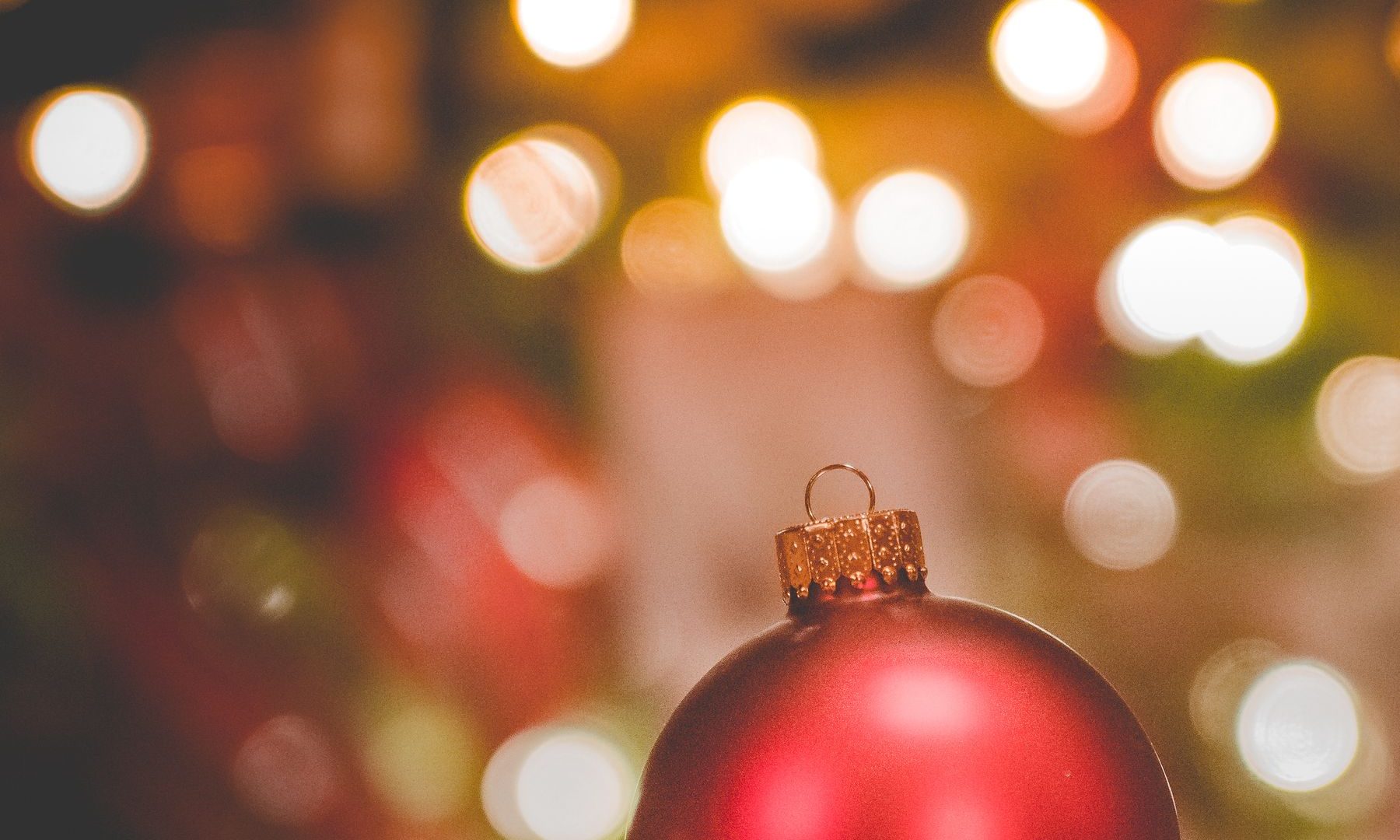 Red Christmas ornament on cloth with warm circular lights blurred behind it