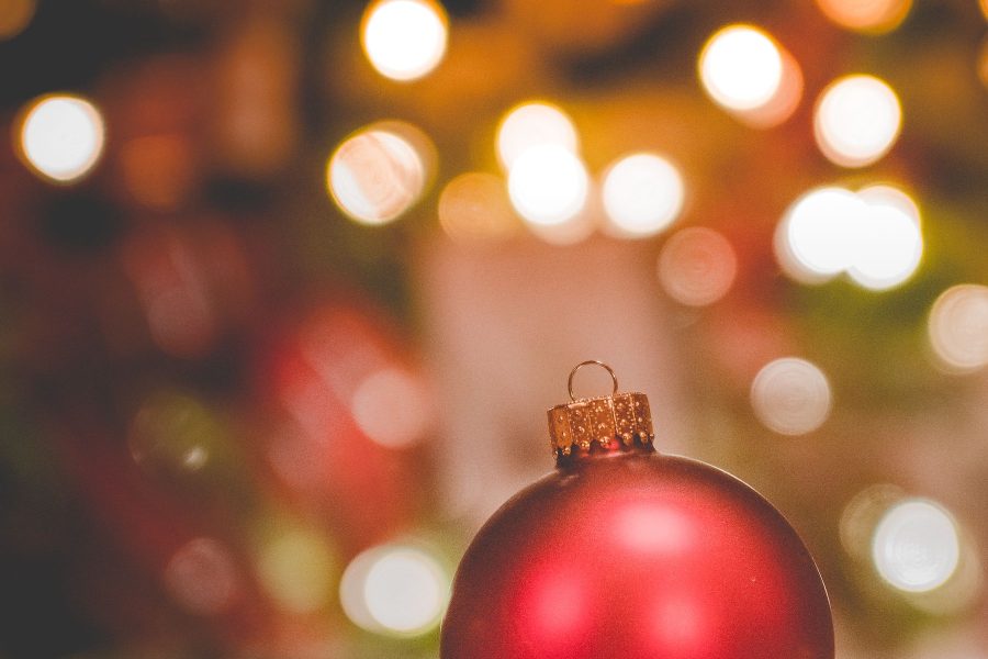 Red Christmas ornament on cloth with warm circular lights blurred behind it