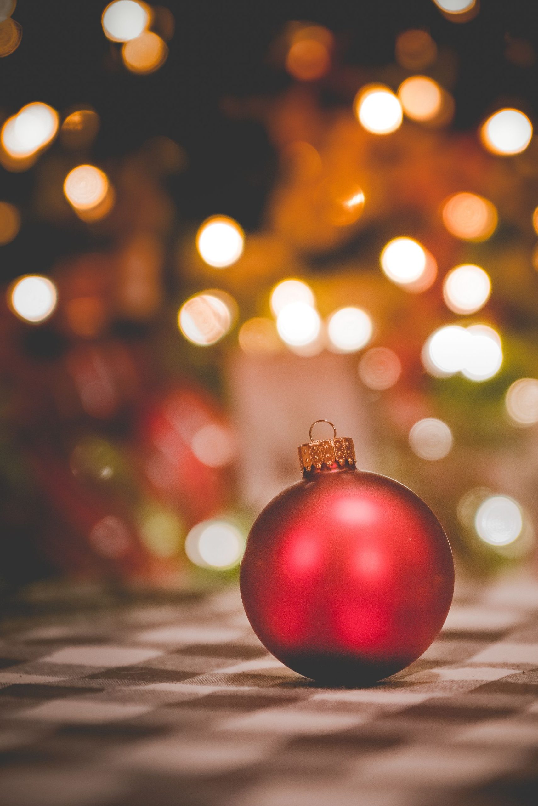 Red ornament in front of large warm circular Christmas lights