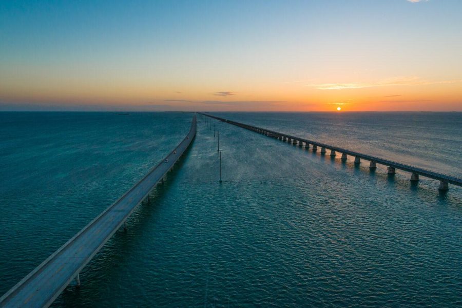 Seven Mile Bridge and parallel bridge spans crossing blue water toward the sunset horizon in the Florida Keys