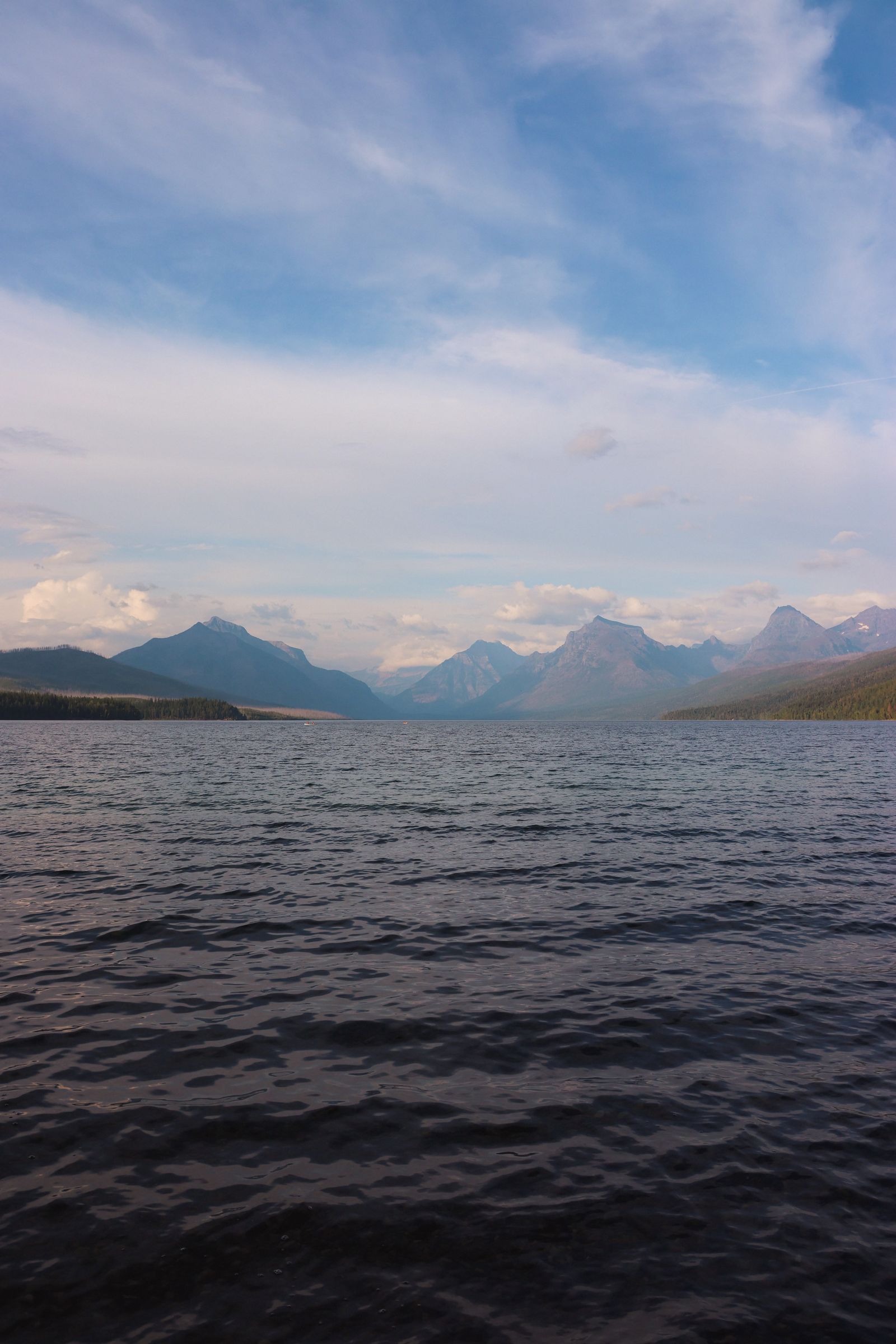 Mountains rising over a Glacier National Park lake under moving cloud
