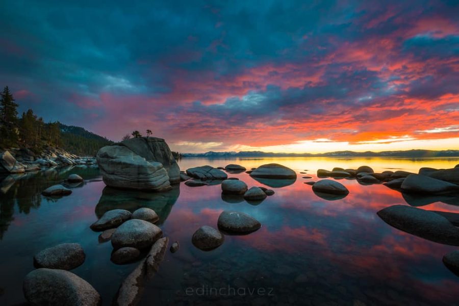 Bonsai Rock and granite boulders reflected in Lake Tahoe beneath orange and pink sunset clouds