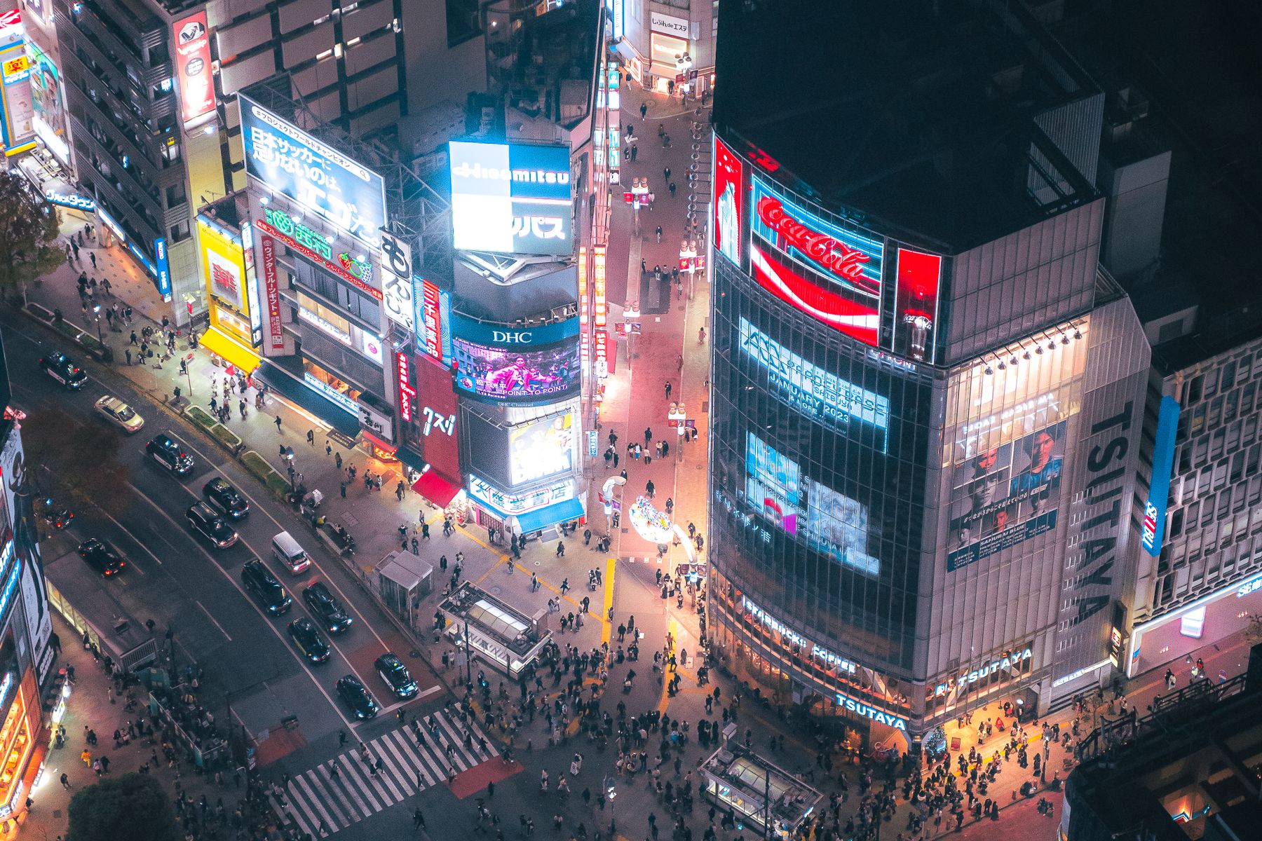 Shibuya Crossing in Tokyo seen from above at night, lit by billboards