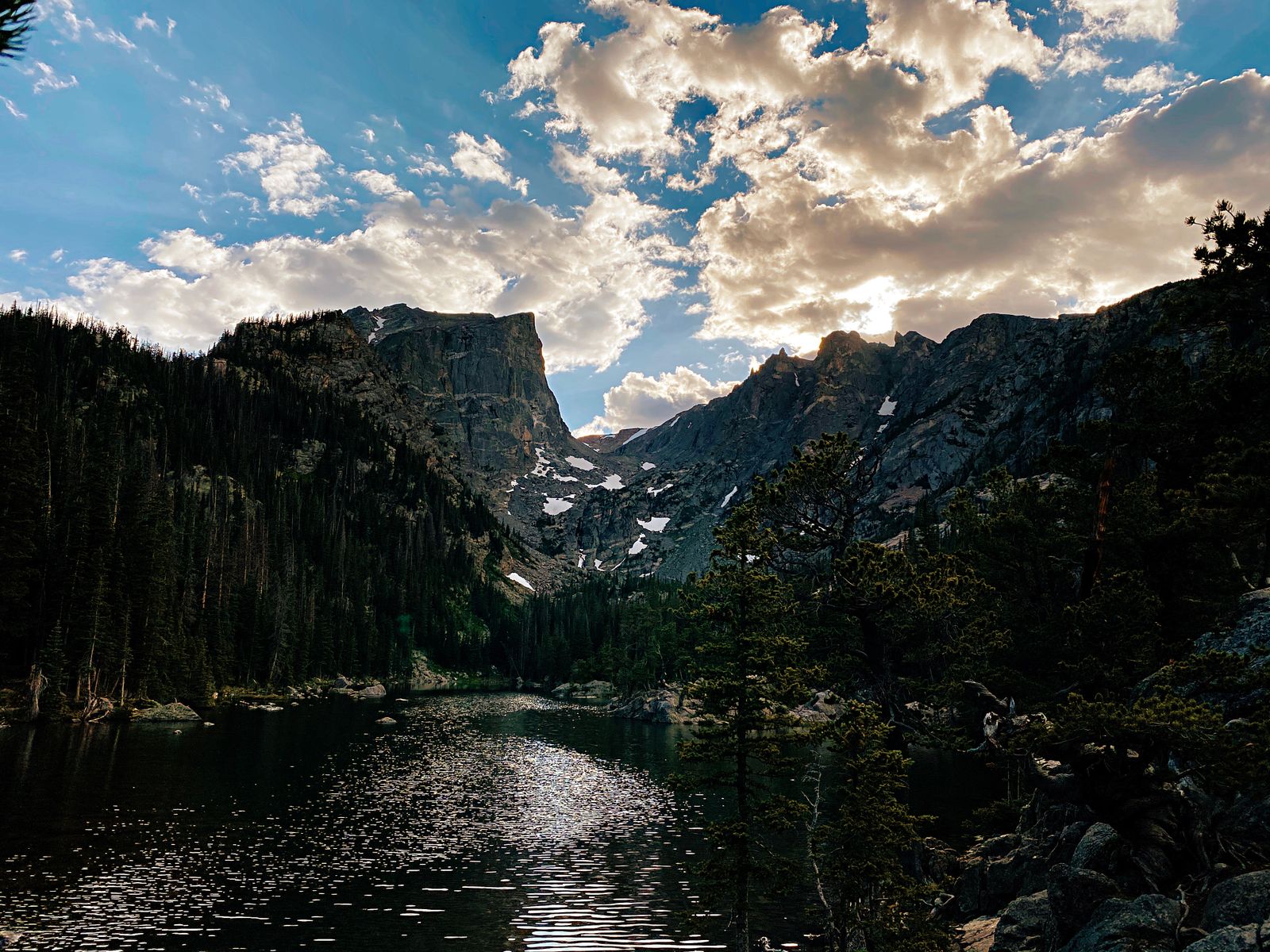 Golden-hour clouds over a backlit alpine lake and peaks in Rocky Mountain National Park