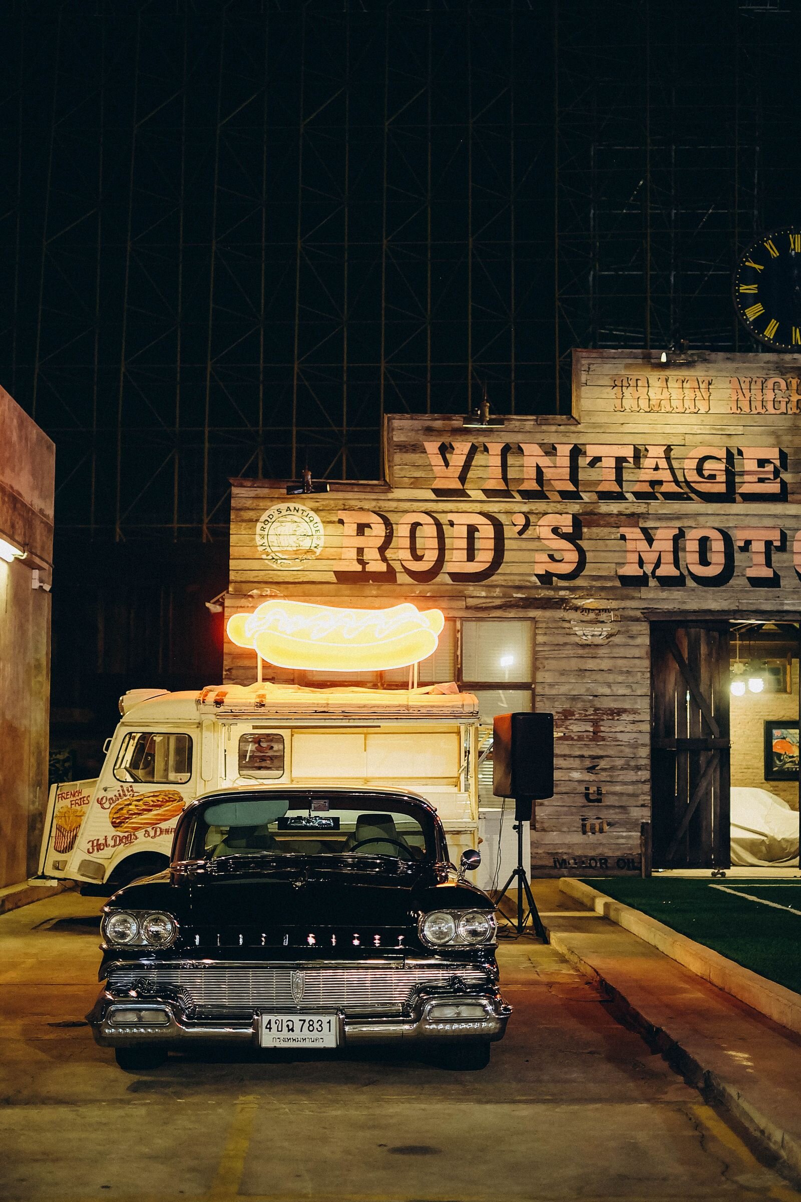 Vintage car parked outside a retro motel with a glowing neon sign at night