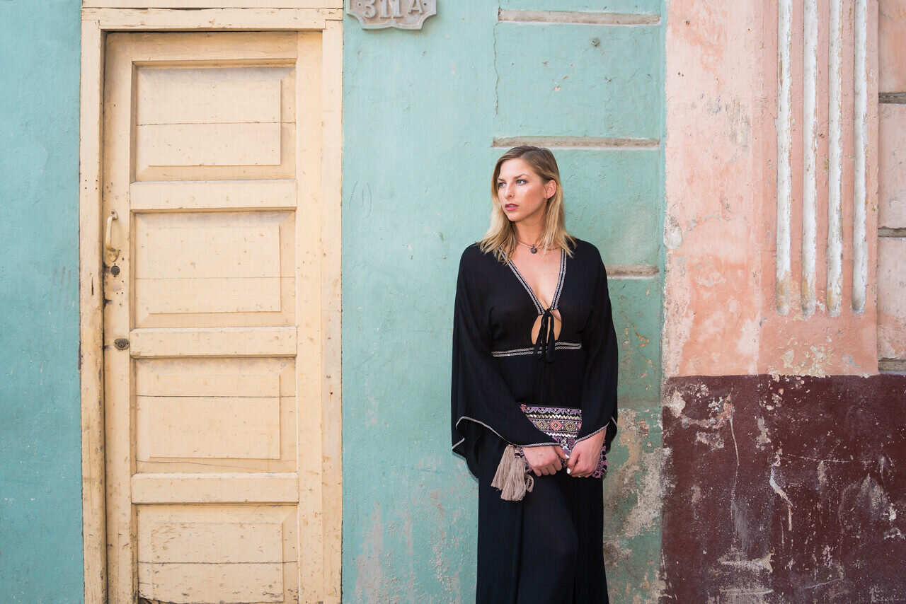 Woman in a black outfit against a textured turquoise and pink wall