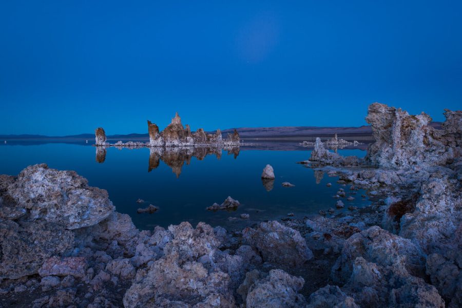 Tufa rock formations beside still blue water at Mono Lake at dusk