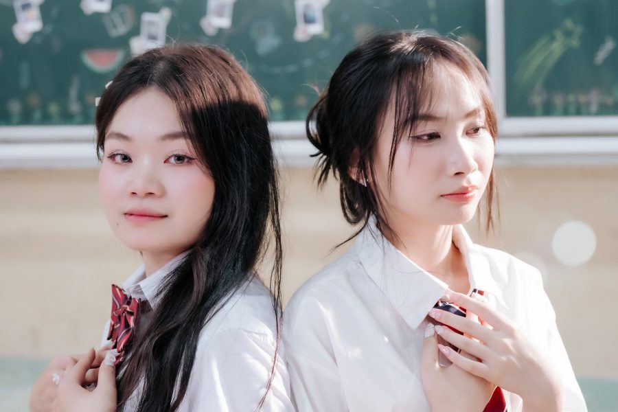 Two students in school uniforms posed in a classroom