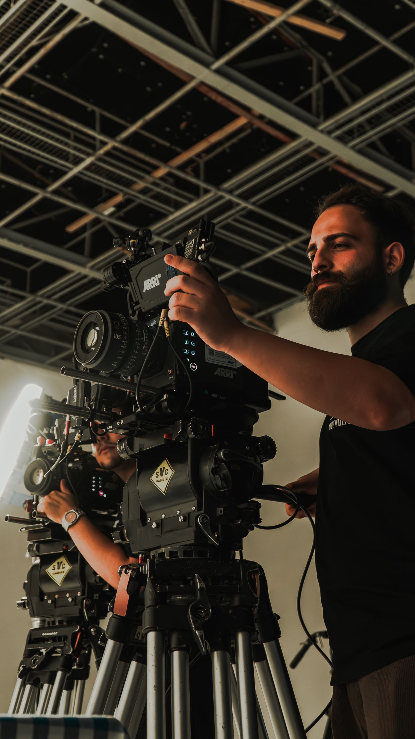 Film crew working with a professional cinema camera on a tripod inside a studio.