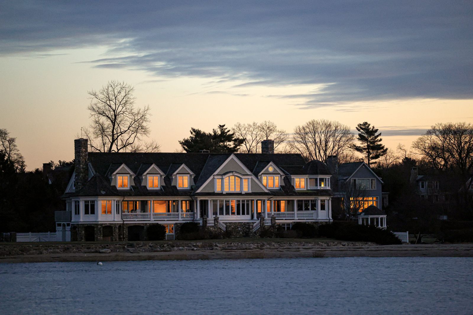 Luxury waterfront estate at twilight with warm lit windows