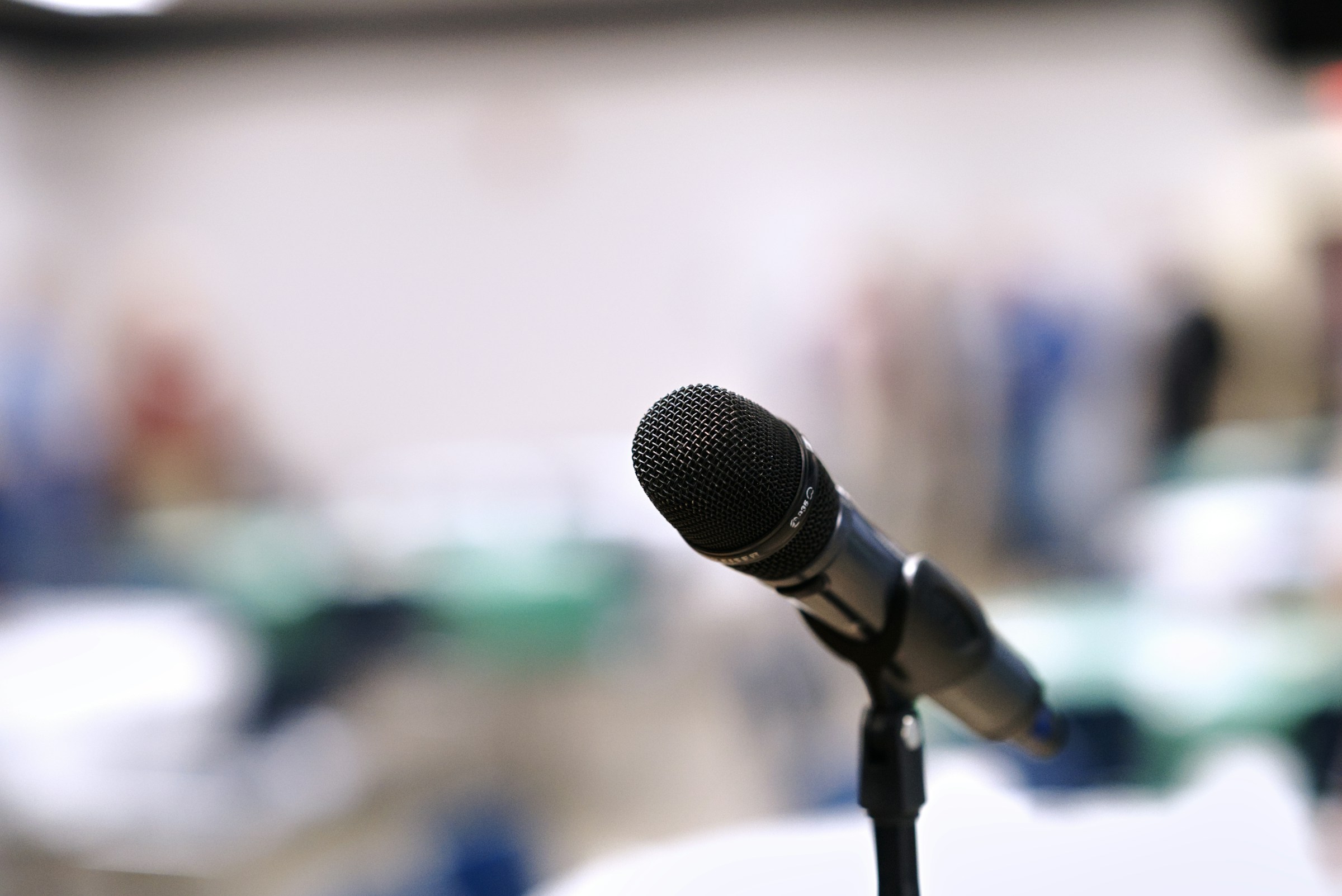 A black handheld microphone on a stand with a softly blurred room in the background