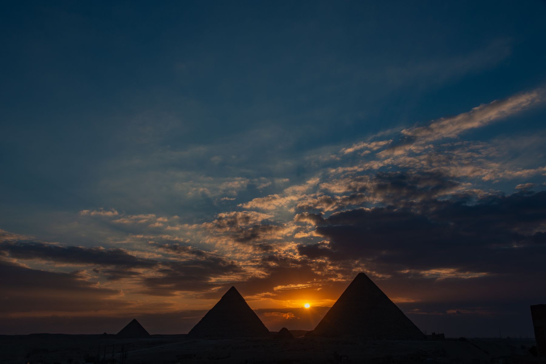 Silhouettes of the Giza pyramids against a golden hour sunset sky