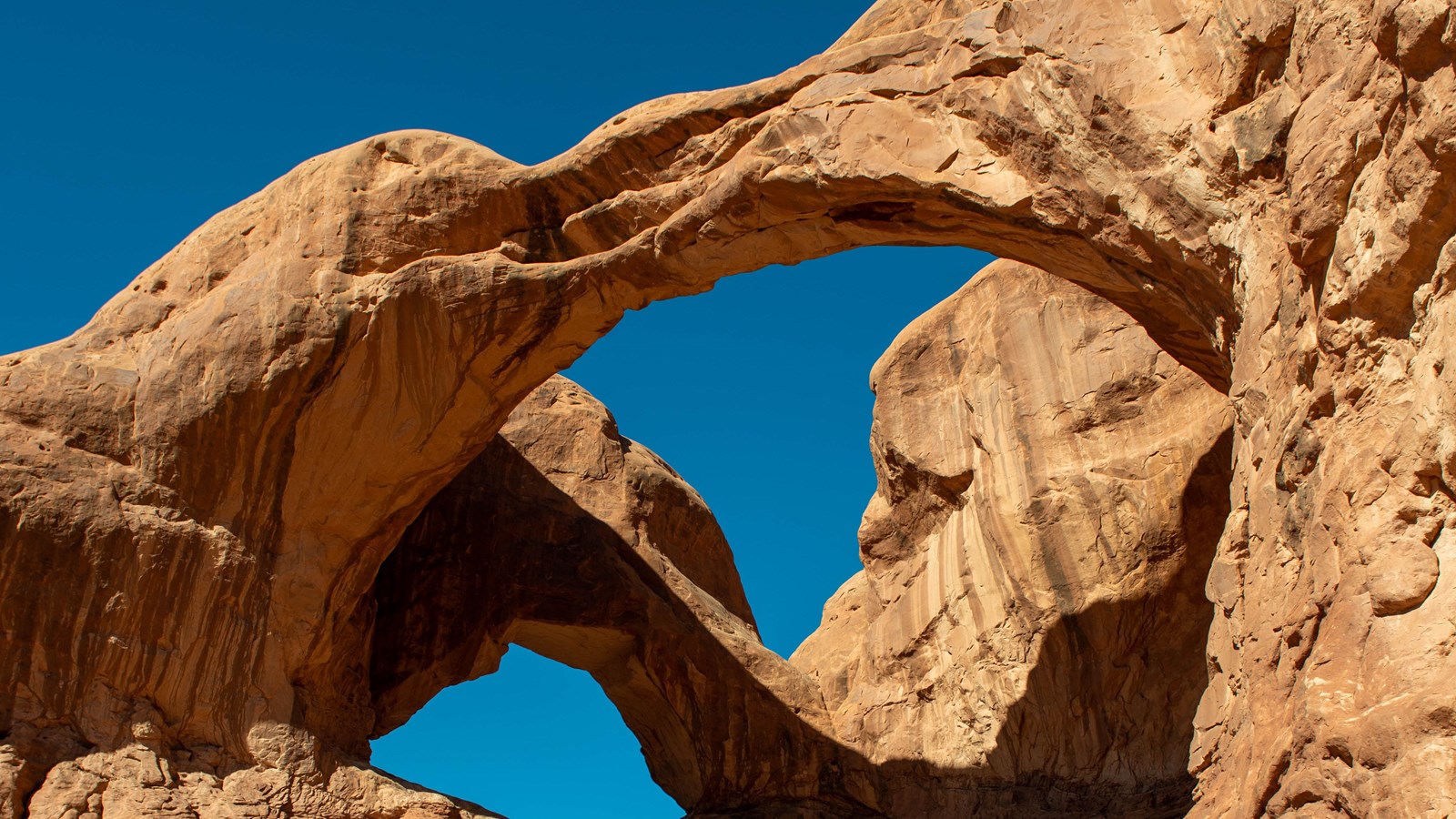 Double Arch sandstone spans against blue sky in Arches National Park