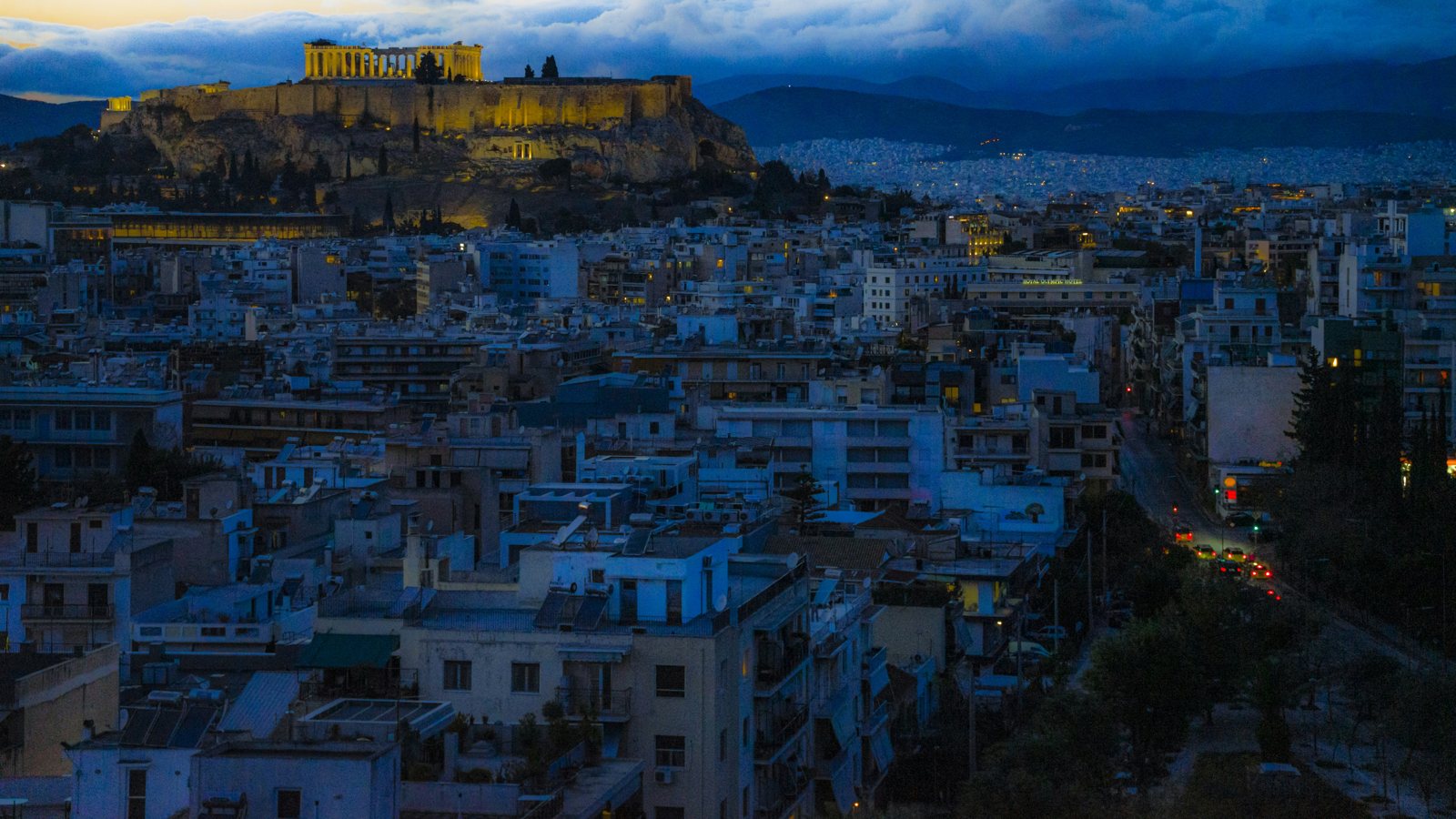 The Acropolis above Athens rooftops at blue hour with a deep blue sky