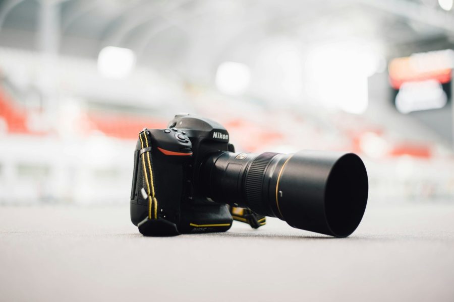 A Nikon DSLR with a zoom lens resting on a light-colored surface.