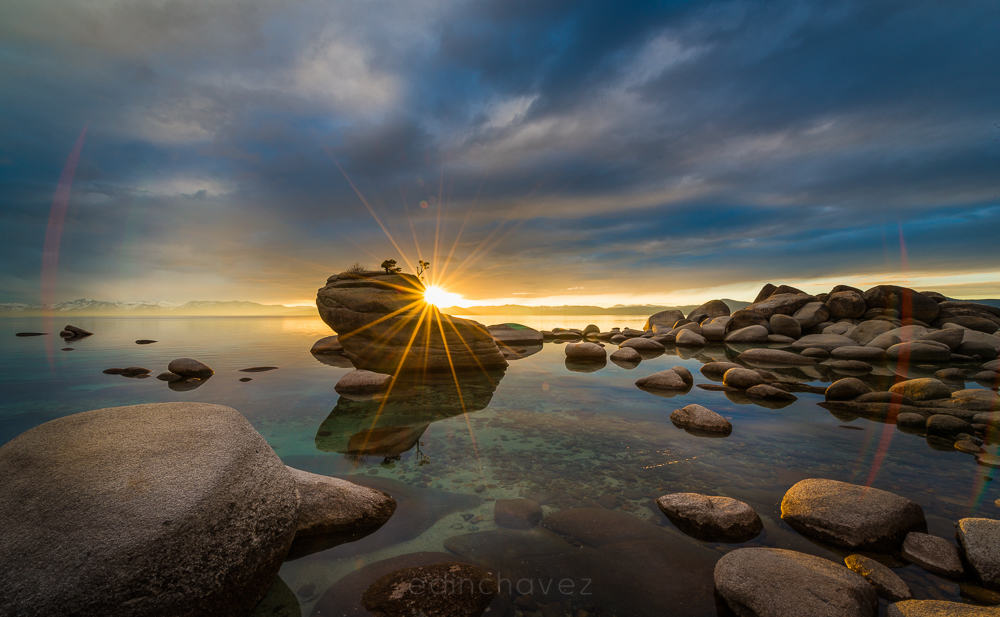 Sunstar beside Bonsai Rock at Lake Tahoe with clear water and foreground granite