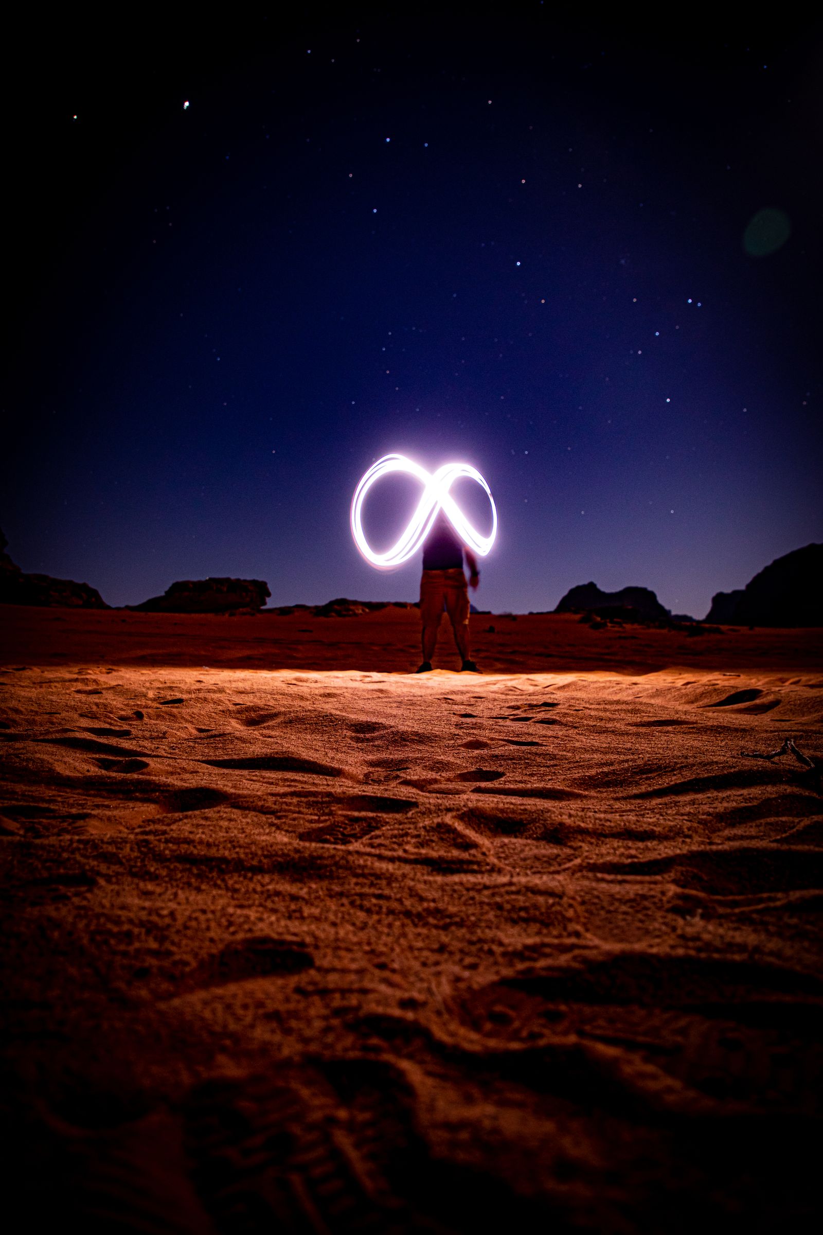 Photographer drawing an infinity sign of light under a starry sky